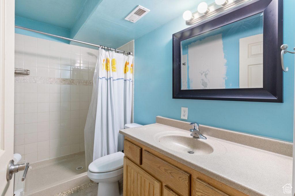 Bathroom with toilet, a stall shower, and vanity