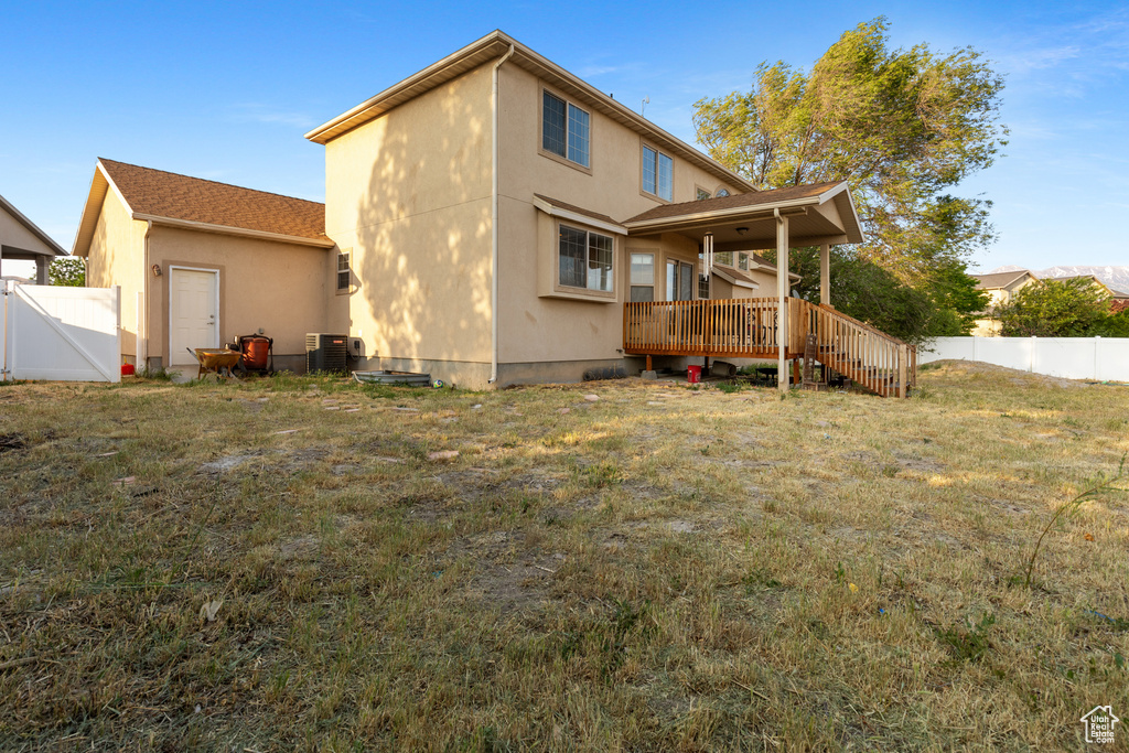 Back of house featuring a wooden deck, stucco siding, and central air condition unit