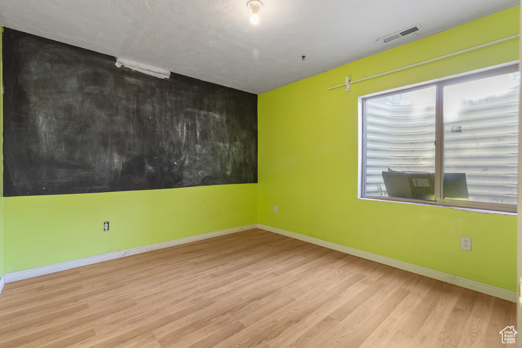 Empty room with wood finished floors, plenty of natural light, and baseboards