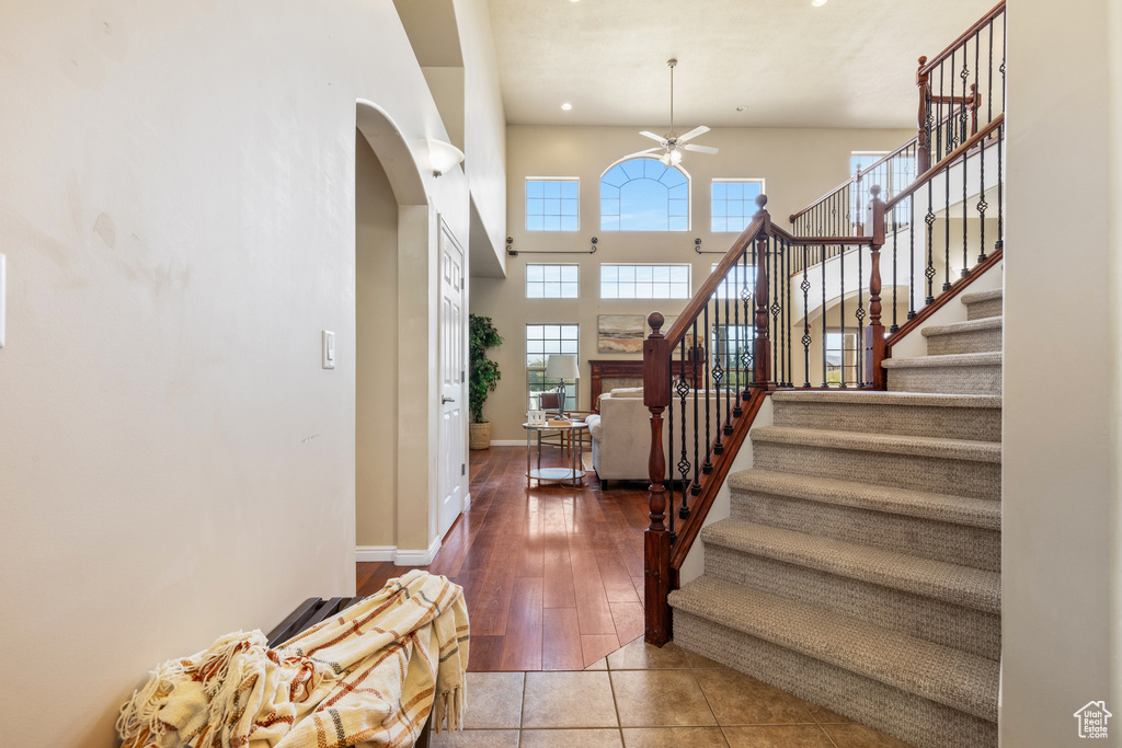 Entryway featuring ceiling fan, arched walkways, stairs, tile patterned flooring, and a high ceiling