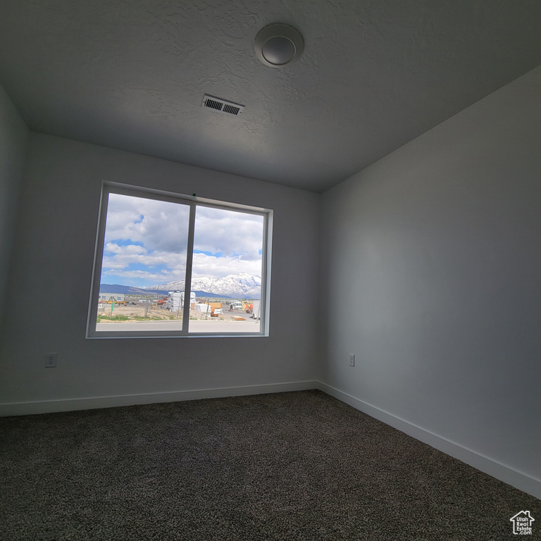 Spare room with baseboards and dark carpet
