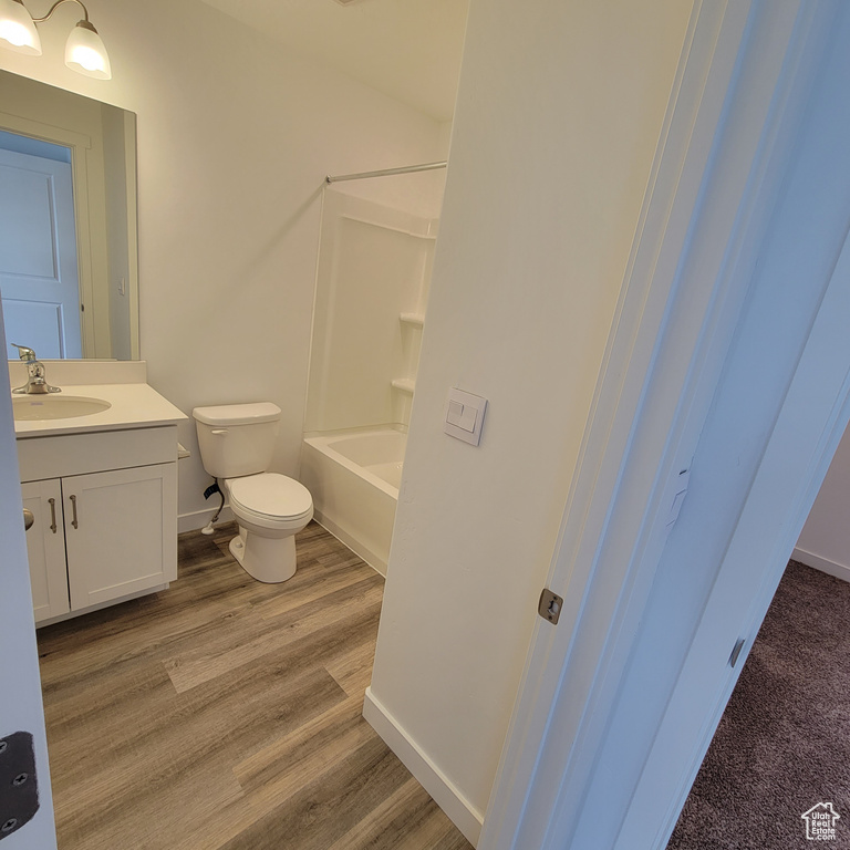 Full bath with vanity, toilet, baseboards, wood finished floors, and bathtub / shower combination