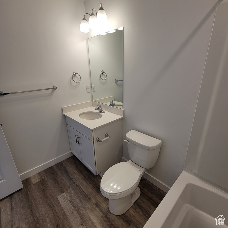 Bathroom featuring wood finished floors, toilet, vanity, and baseboards