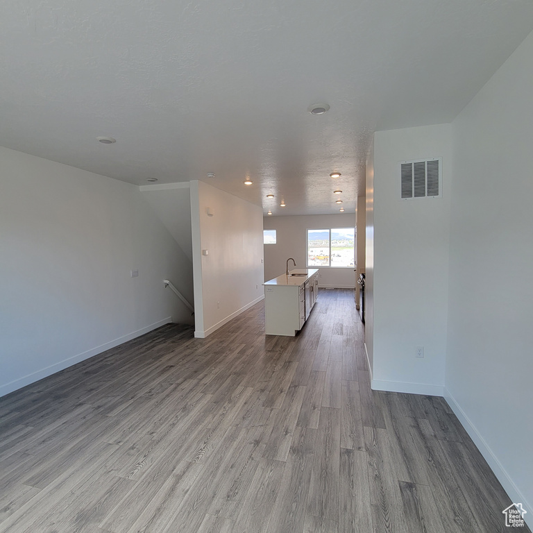 Unfurnished living room with wood finished floors, baseboards, and recessed lighting