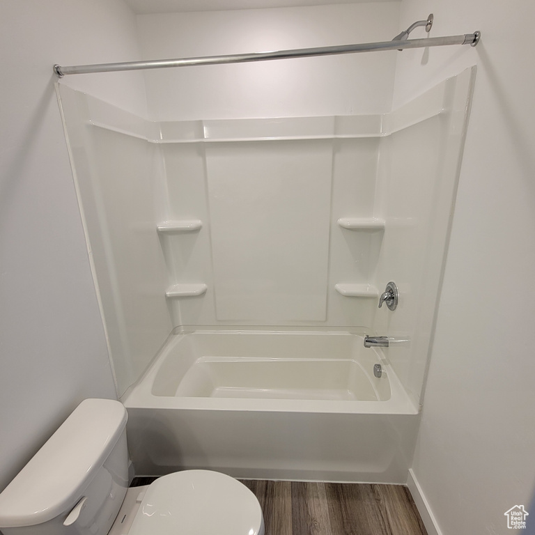 Full bath featuring toilet, wood finished floors, and shower / bath combination