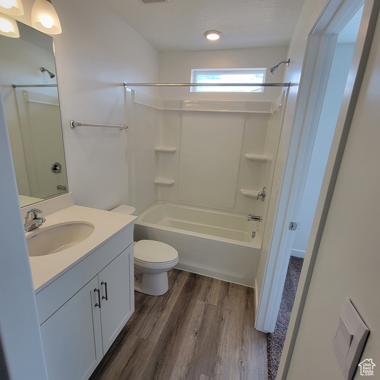 Full bath with vanity, wood finished floors, shower / bath combination, toilet, and recessed lighting