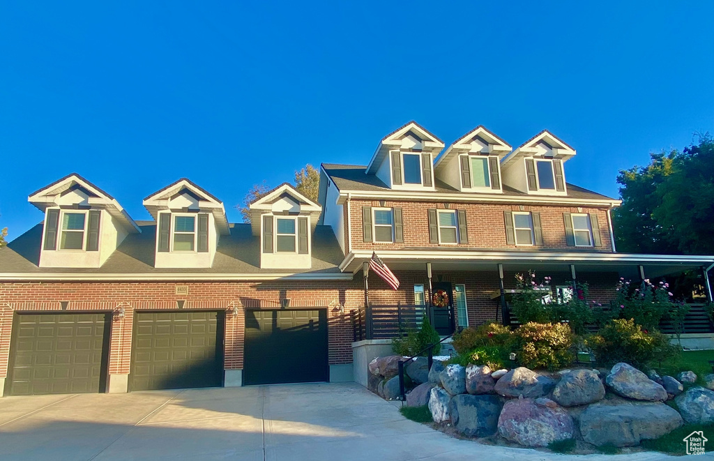 View of front of house featuring brick siding, a garage, driveway, and a porch