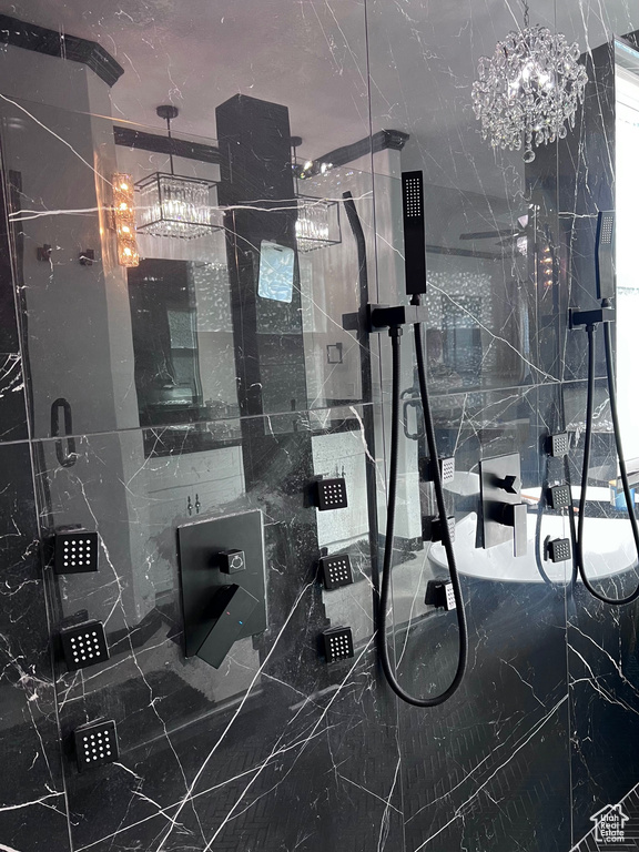 Bathroom view of a marble finish shower and a chandelier