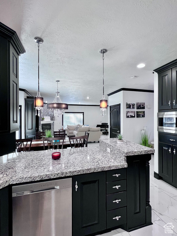 Kitchen featuring appliances with stainless steel finishes, dark cabinets, light marble finish floors, open floor plan, and a textured ceiling