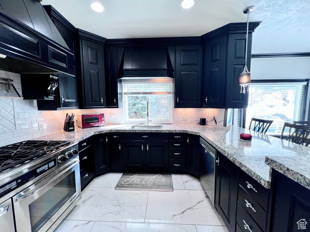 Kitchen featuring appliances with stainless steel finishes, dark cabinetry, backsplash, light stone counters, and recessed lighting