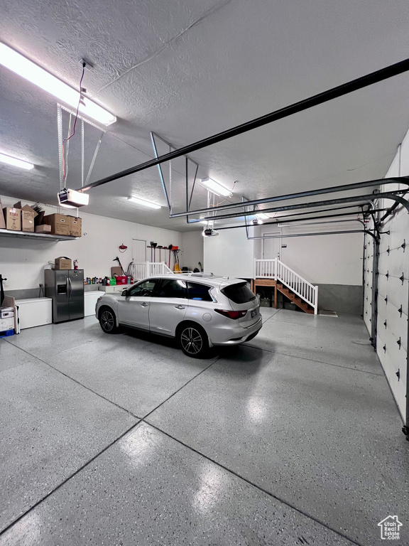 Garage featuring stainless steel fridge and a garage door opener