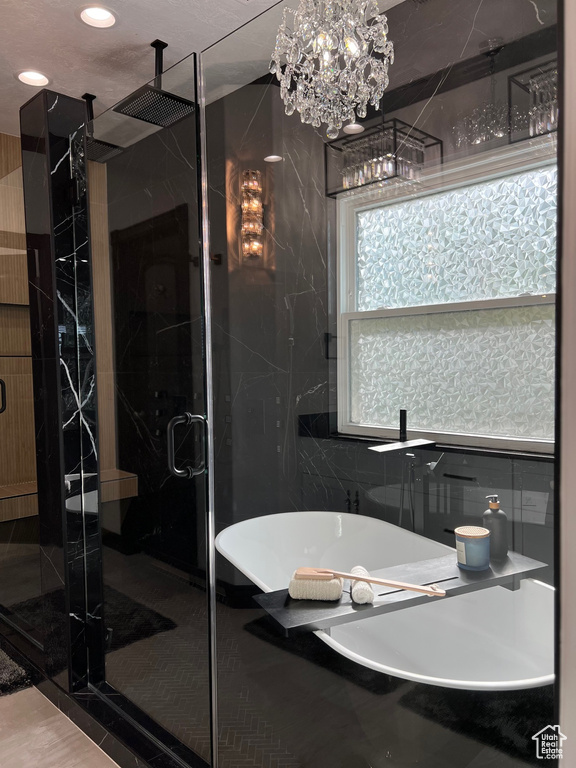 Full bath with a shower stall, a freestanding bath, a chandelier, and recessed lighting