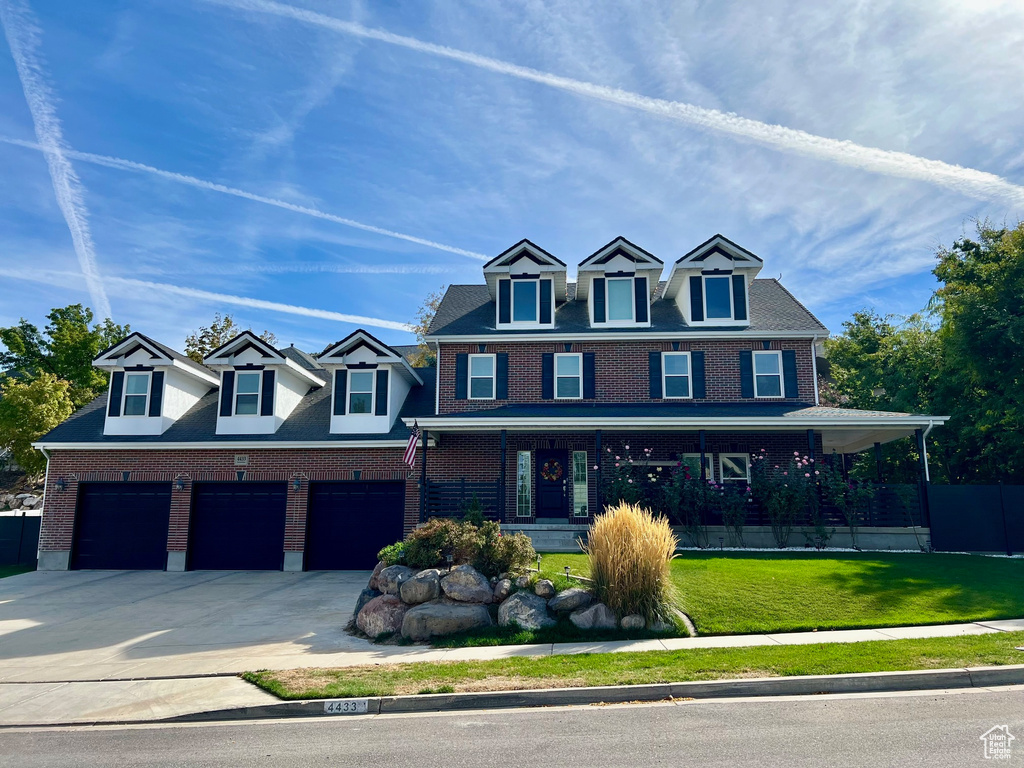 View of front facade with a porch, a garage, concrete driveway, and brick siding