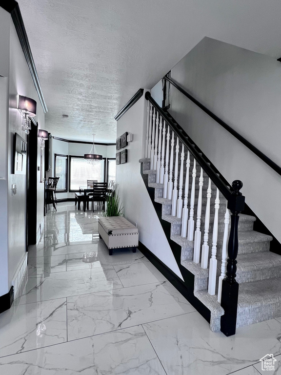 Stairway featuring baseboards, a textured ceiling, and marble finish floors