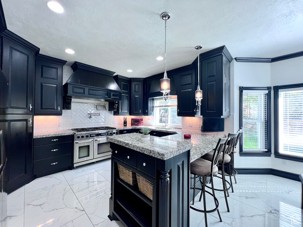 Kitchen with range with two ovens, light marble finish floors, custom exhaust hood, a textured ceiling, and tasteful backsplash