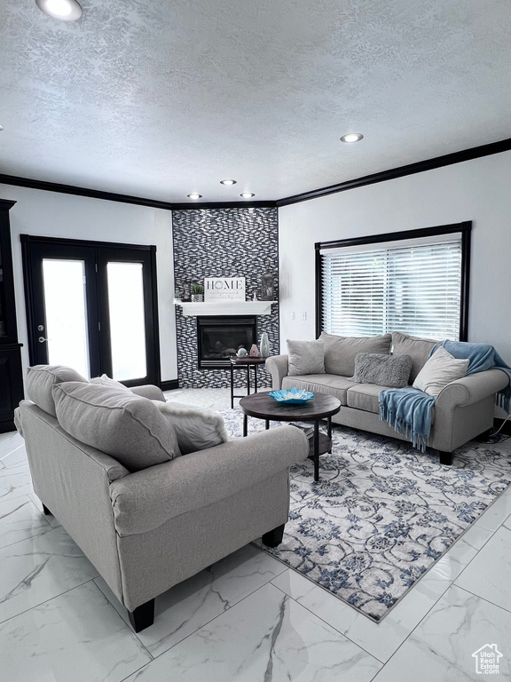 Living area featuring crown molding, light marble finish flooring, a textured ceiling, recessed lighting, and a glass covered fireplace