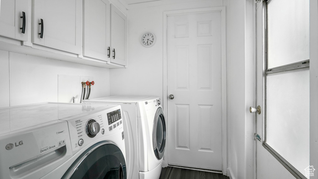 Laundry area featuring separate washer and dryer, cabinet space, and dark wood-style flooring