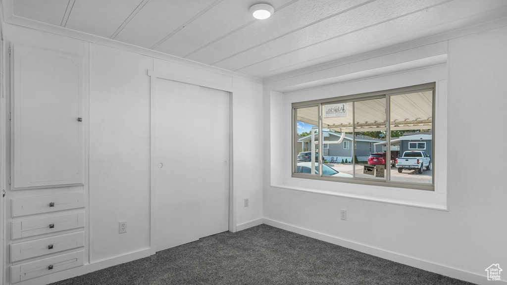Unfurnished bedroom featuring dark carpet, a closet, and baseboards