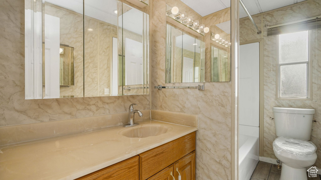 Full bathroom with vanity, tile walls, toilet, and bathing tub / shower combination