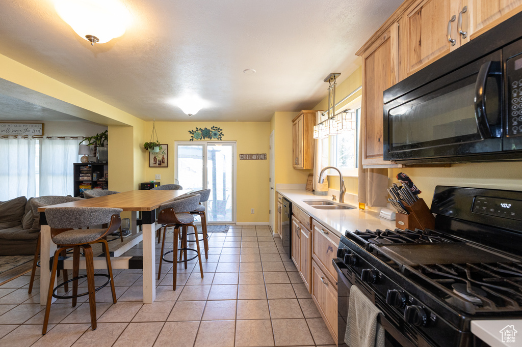 Kitchen with black appliances, a sink, light countertops, and plenty of natural light
