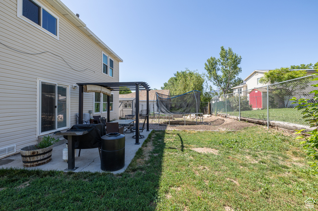 View of yard with a trampoline, a pergola, and a patio