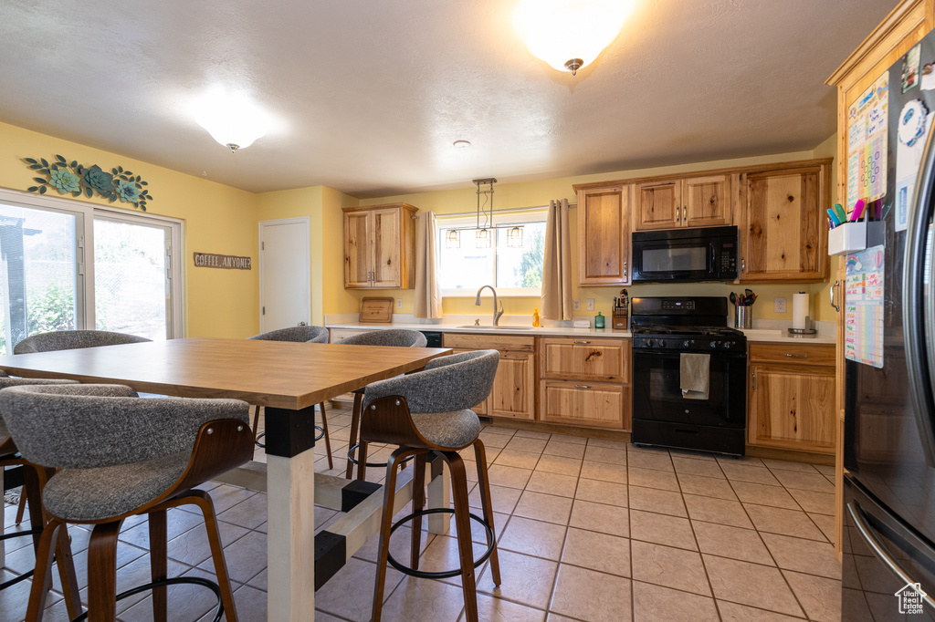 Kitchen with black appliances, light countertops, a sink, and light tile patterned floors