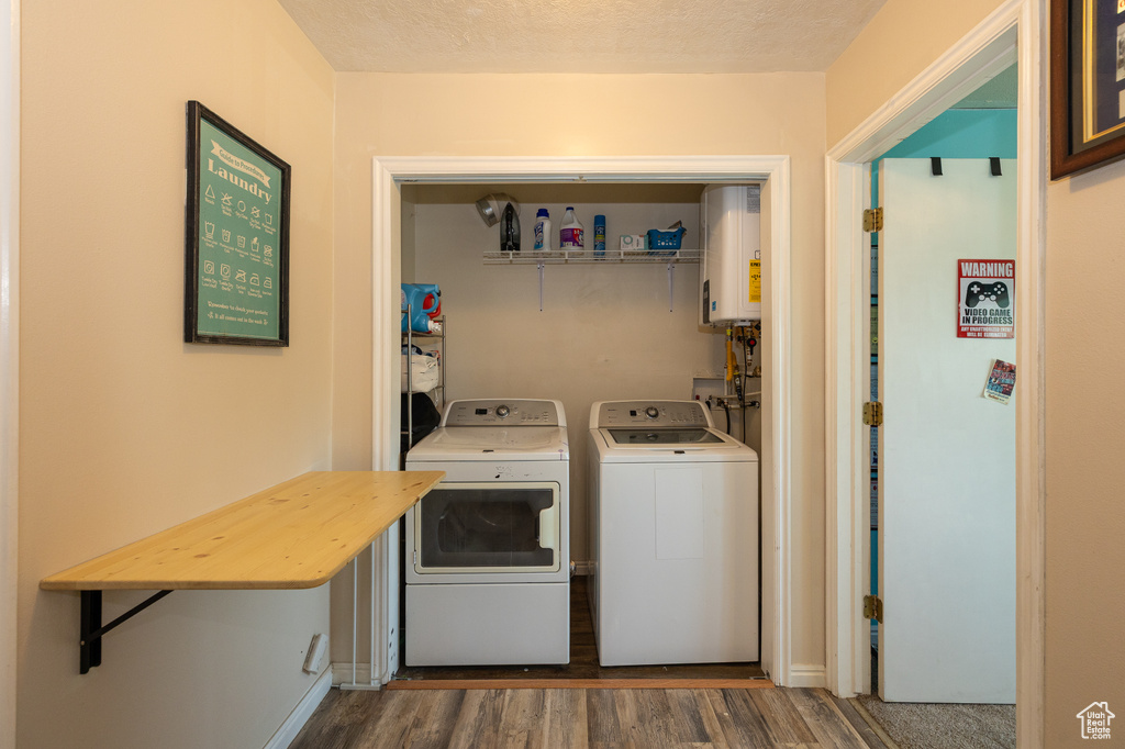 Laundry area with washer and clothes dryer, water heater, wood finished floors, and a textured ceiling
