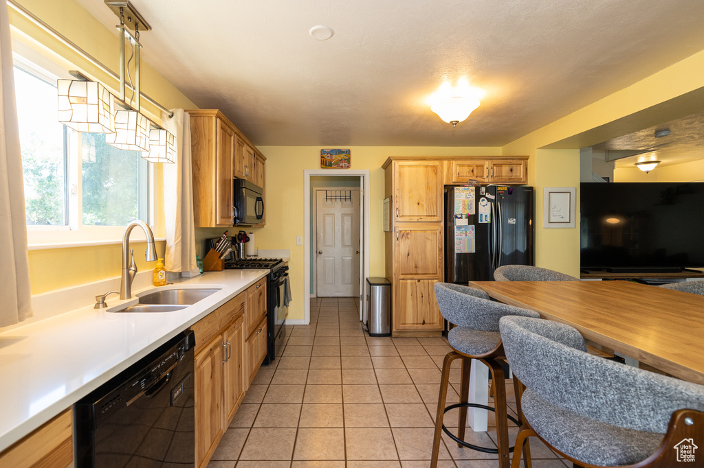 Kitchen with black appliances, a sink, light countertops, and light tile patterned flooring