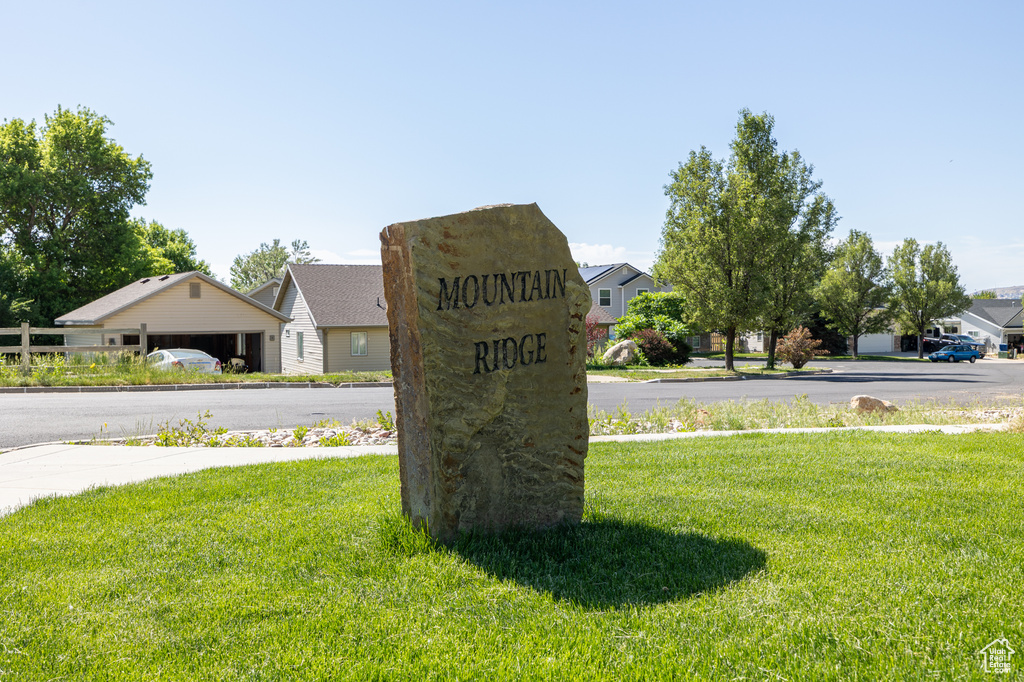 Community sign featuring a yard and a residential view