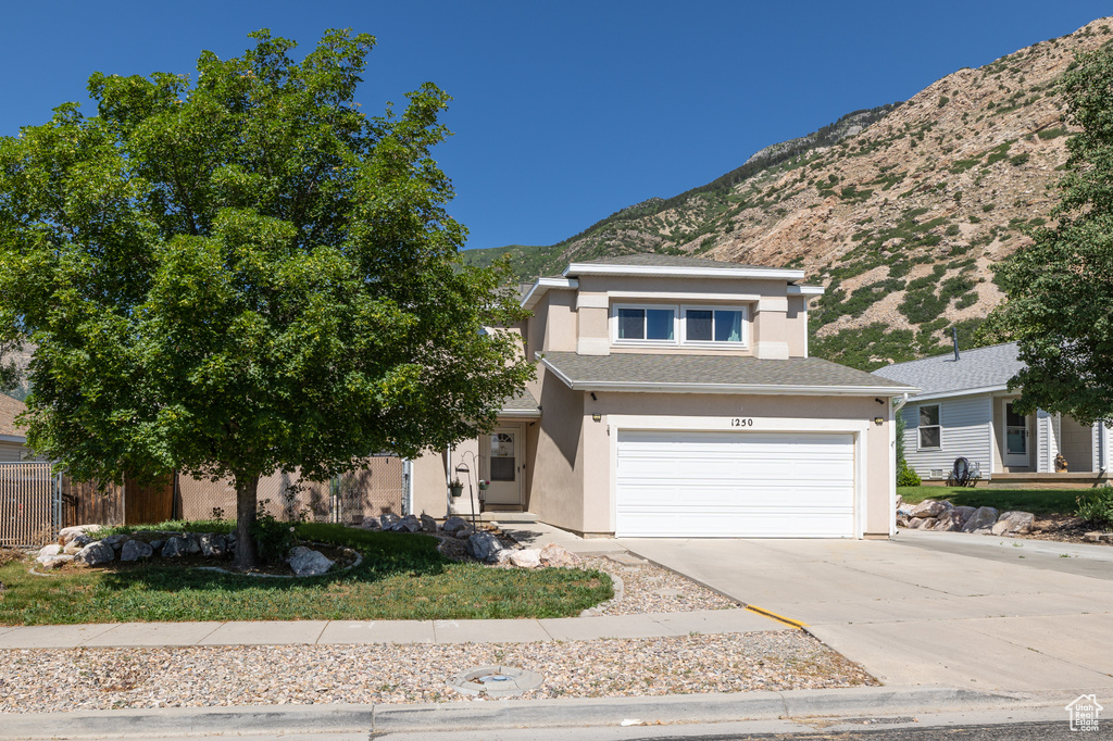 View of front of home with a mountain view, stucco siding, concrete driveway, and an attached garage