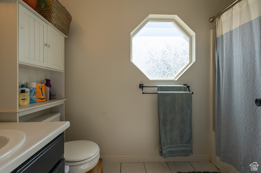 Bathroom featuring tile patterned flooring, vanity, toilet, baseboards, and a shower with curtain