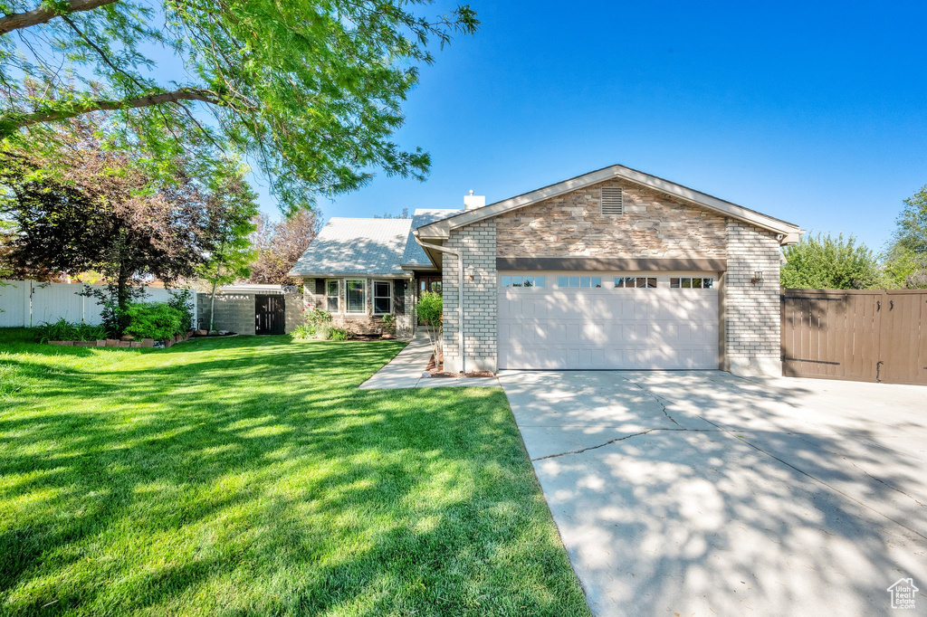 View of front of house with driveway, an attached garage, a gate, and brick siding