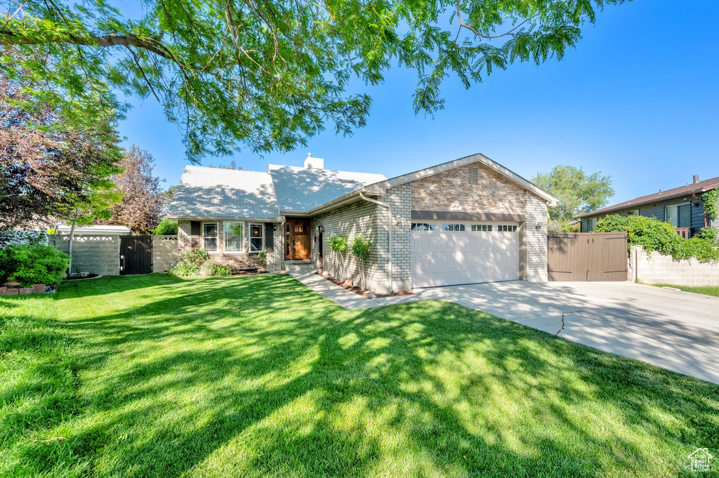 View of front of property with concrete driveway, an attached garage, a gate, a chimney, and brick siding