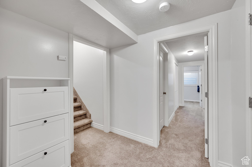 Corridor featuring light colored carpet and baseboards