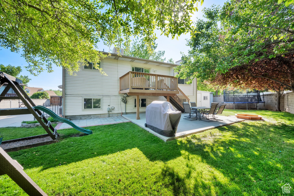 Rear view of property with a trampoline, a patio, a wooden deck, and stairs