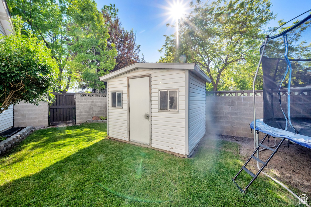 View of shed featuring a trampoline and a gate