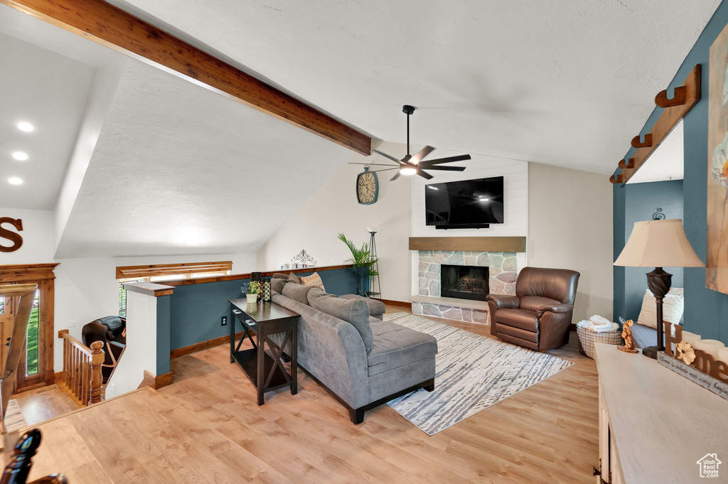 Living room featuring ceiling fan, light wood-type flooring, a fireplace, recessed lighting, and baseboards