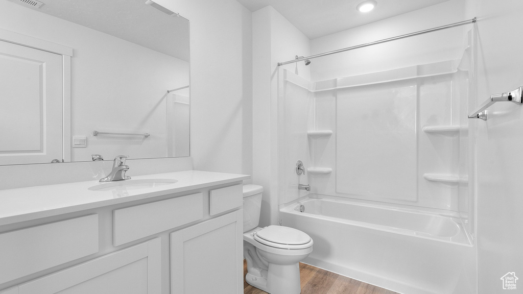 Full bathroom featuring toilet, wood finished floors, shower / bathtub combination, vanity, and recessed lighting