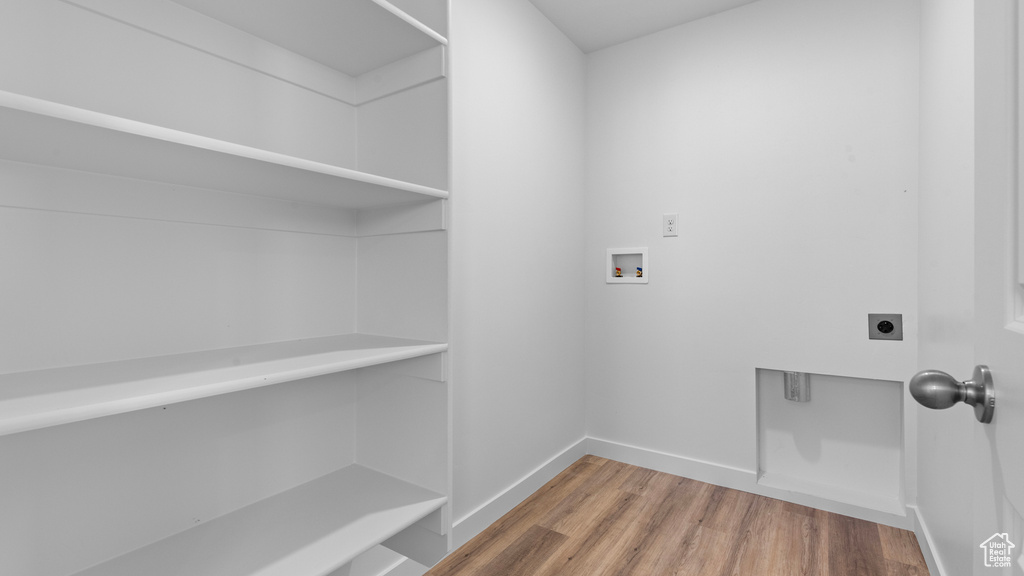 Laundry room featuring electric dryer hookup, hookup for a washing machine, light wood-style floors, and baseboards