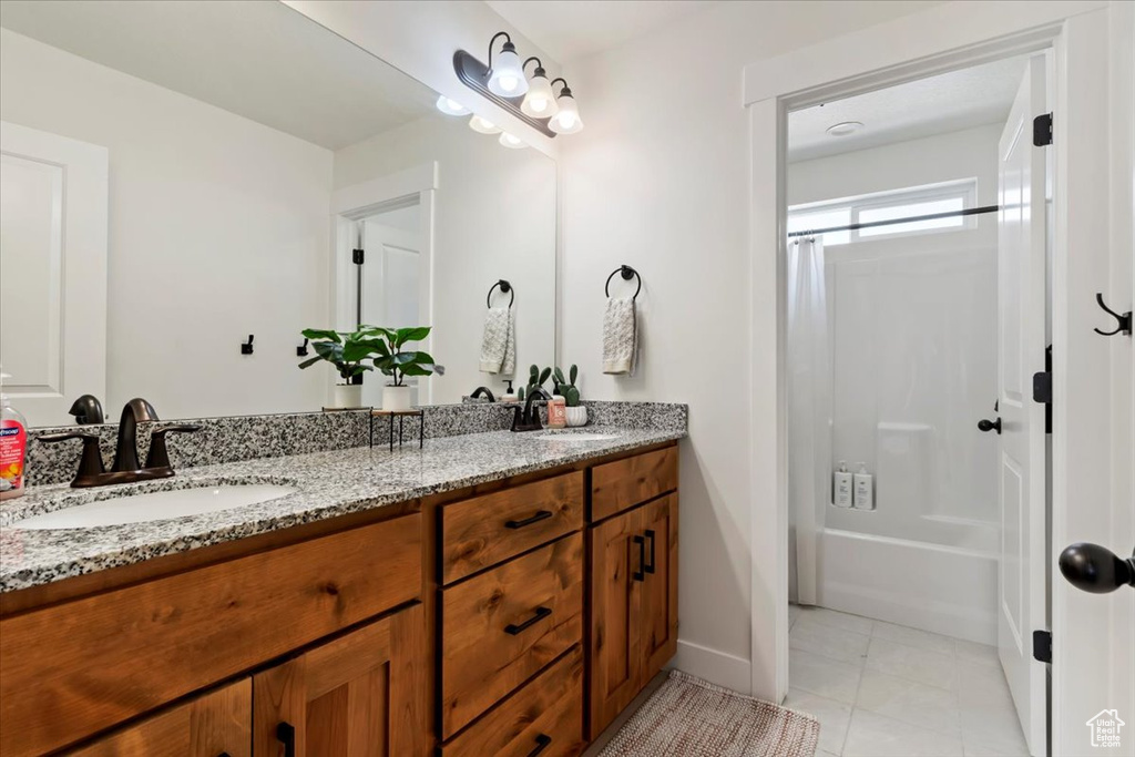 Full bathroom with double vanity, shower / bath combo with shower curtain, tile patterned floors, and baseboards
