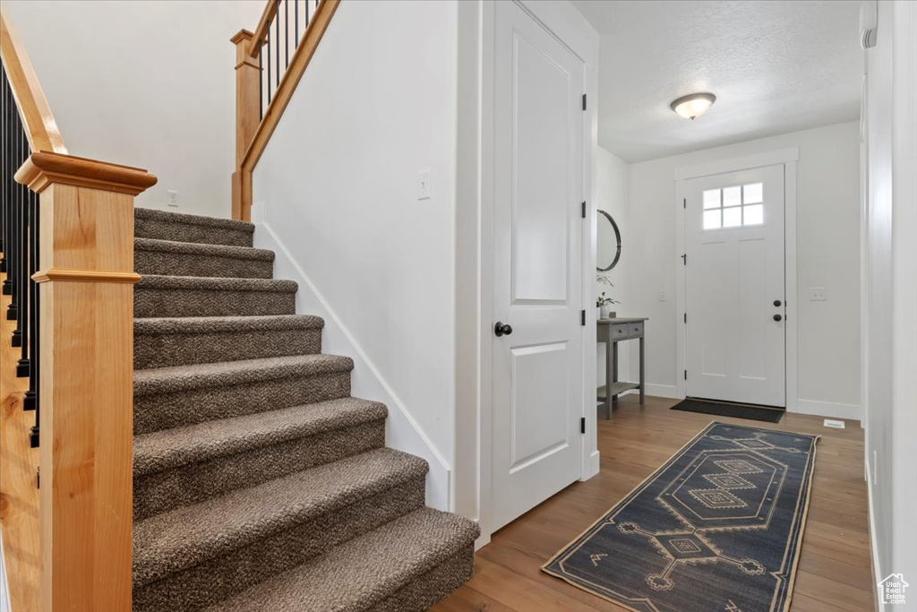 Entryway featuring stairs, wood finished floors, and baseboards