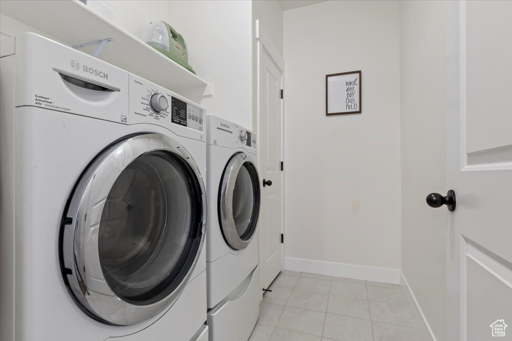 Washroom with washer and clothes dryer, baseboards, and light tile patterned flooring
