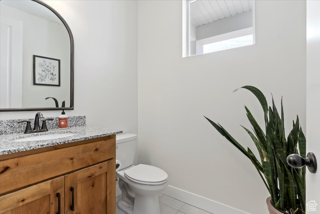 Bathroom with toilet, tile patterned floors, and vanity