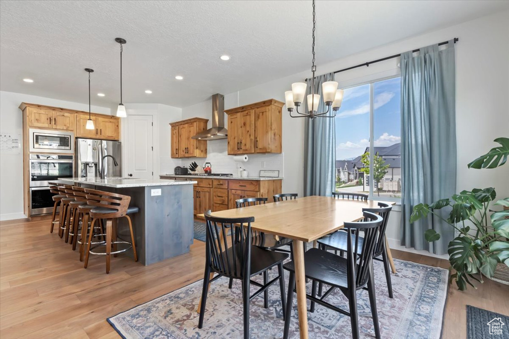 Dining room with light wood-style flooring, a chandelier, recessed lighting, baseboards, and a textured ceiling