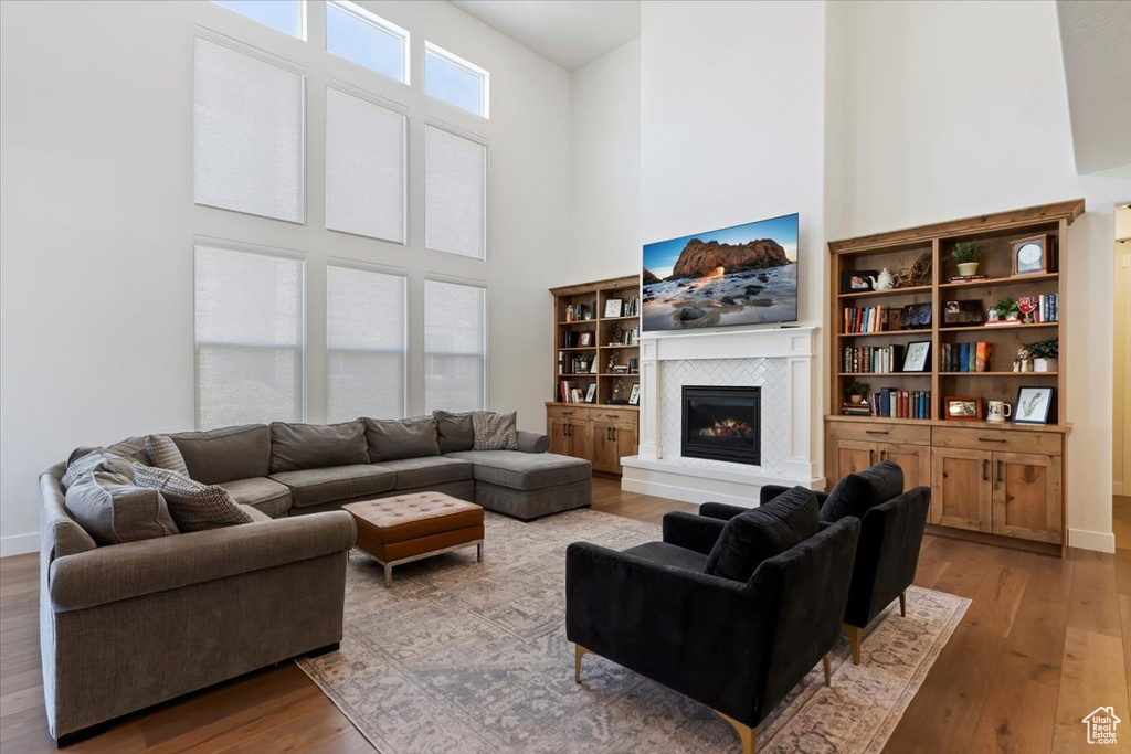 Living area featuring a high ceiling, wood-type flooring, and a fireplace