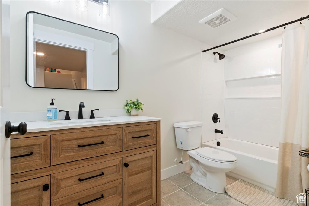 Bathroom with vanity, tile patterned flooring, toilet, shower / bath combo, and baseboards