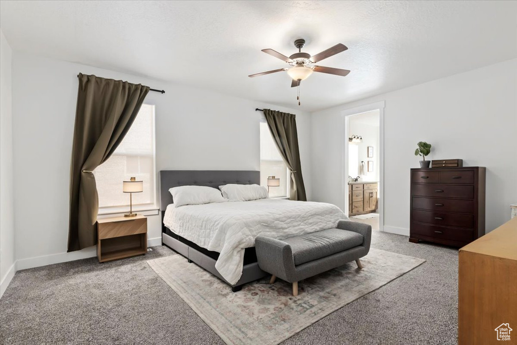 Bedroom with light colored carpet, baseboards, and connected bathroom