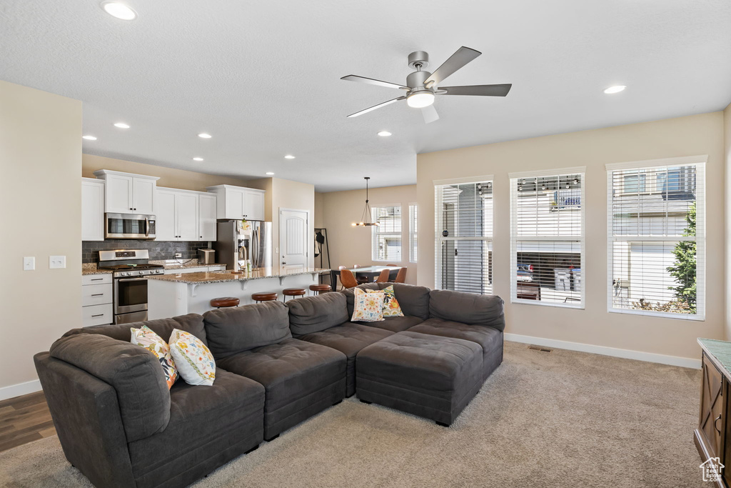Living area featuring ceiling fan, recessed lighting, baseboards, and light colored carpet