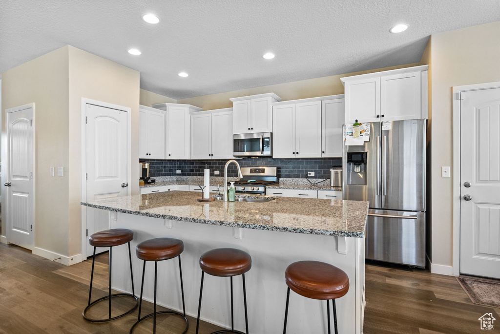Kitchen featuring appliances with stainless steel finishes, dark wood-type flooring, white cabinetry, baseboards, and recessed lighting