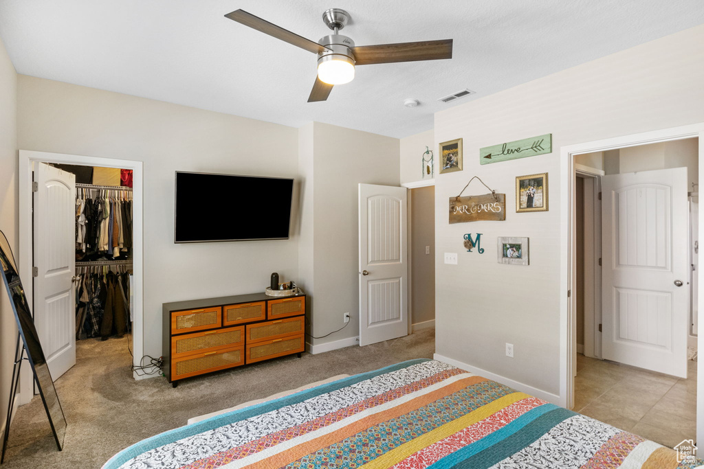 Carpeted bedroom with a spacious closet, baseboards, a closet, and ceiling fan